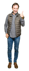 Sticker - Middle age handsome man wearing winter vest doing happy thumbs up gesture with hand. Approving expression looking at the camera showing success.