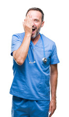 Sticker - Middle age hoary senior doctor man wearing medical uniform over isolated background covering one eye with hand with confident smile on face and surprise emotion.