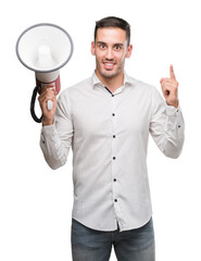 Sticker - Handsome young man holding microphone surprised with an idea or question pointing finger with happy face, number one