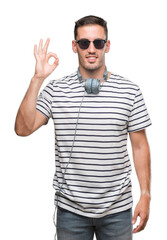 Sticker - Handsome young man wearing headphones smiling positive doing ok sign with hand and fingers. Successful expression.