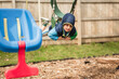 Happy child swinging on belly on swing in coat on playground