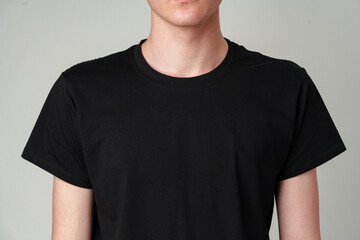 Wall Mural - Young Man Wearing a Plain Black T-Shirt Against a Gray Background