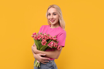 Wall Mural - Happy young woman with beautiful bouquet on orange background