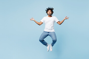 Wall Mural - Full body young happy Indian man wear white t-shirt casual clothes jump high hold spreading hands in yoga om aum gesture relax meditate try to calm down isolated on plain light blue cyan background.