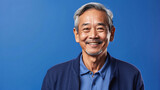 Fototapeta  - Elderly Asian man with a kindly smile and a casual blue shirt, conveying warmth and friendliness