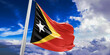 East Timor (Timor-Leste) national flag cloth fabric waving on beautiful Blue Sky Background.