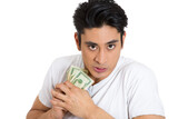 Fototapeta Do pokoju - portrait of a greedy young  man, holding dollar banknotes tightly, isolated on white background.