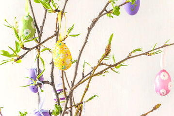 Wall Mural - Easter holiday concept; Twigs decorated by easter eggs on a white background; selective focus