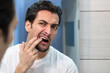 © Vitaliy - Young handsome man checking up his teeth in front of the mirror in the bathroom