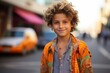 © MediaRaw - A young boy with curly hair is wearing an orange shirt and smiling