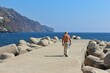 Back view of a man walking on a pier by an ocean in Madeira on a sunny day