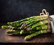 A bundle of fresh green asparagus tied with twine, laid on a dark surface adorned with herbs and droplets. The lighting is soft yet highlights the freshness and details of the asparagus.