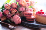Fototapeta Kosmos - Beautiful pink bouquet of flowers with sweet delicacies. Sweet pastries with pink roses and tulips on a wooden table. Background for mother's day and weddings. Close-up.