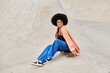 A curly-haired African American woman sits on a skateboard in a vibrant skate park, exuding urban coolness.