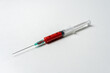 Syringe with red liquid on white background. Minimal Coronavirus outbreak. Pandemic concept.