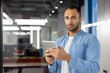© Tetiana - Portrait of a serious young Latin American man standing in the office, holding a tablet and looking at the camera