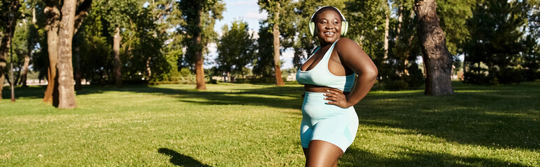 An African American woman, body positive and elegant, stands confidently on lush green grass.