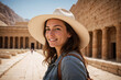 Young woman on travel vacation marveling at historical buildings and architecture of ancient Egypt. A female tourist sightseeing, enjoying her visit to the ruins of the Egyptian Temple of Hatshepsut.