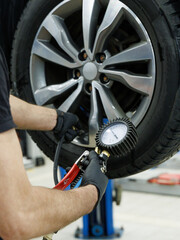 Close up of mechanic's hand checking the air pressure of a tyre in auto repair service