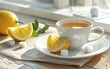 A deliciously hot cup of lemon herbal tea placed on a delicate saucer with a white plate beside it. A slice or half of typical organic lemons and sugar cubes lie next to the teacup