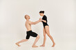 © LIGHTFIELD STUDIOS - A shirtless young man and a woman performing intricate dance poses and acrobatic elements in a studio setting against a white background.