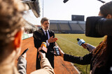 Fototapeta Kuchnia - Interview of private investor at press conference for TV news in soccer stadium. Director of football team answering press questions and giving interview. Inspirational speech during press campaign.