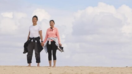 Wall Mural - A couple is standing on a beach holding hands