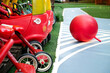 Colorful playground equipment with red toy cars and a ball on artificial turf 