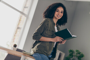 Poster - Photo of pretty young woman toothy smile hold book wear khaki shirt modern interior house indoors