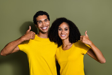 Wall Mural - Photo of two young people show thumb up wear t-shirt isolated on khaki color background