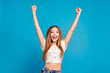 Photo of positive cheerful girl raise fists up isolated blue color background