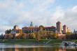 Krakow, Poland. 09.10.2022 Historic Wawel Castle at dawn in autumn, floating ships, restaurants on the Vistula River.