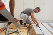 Two mature men installing laminate flooring in a new home together. DIY concept. Professional renovation of a house.