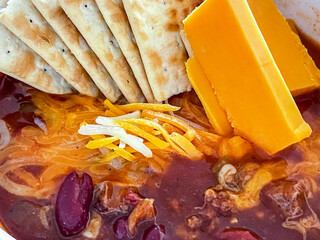 Wall Mural - Cheddar cheese and soda crackers in a bowl of chili with beans and bokeh