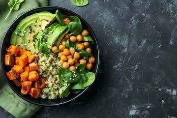Wall Mural - Top view of salad in black bowl with avocado quinoa sweet potato spinach chickpeas