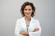 © Johnovich - Portrait of a confident female doctor with arms crossed, isolated on a light gray background