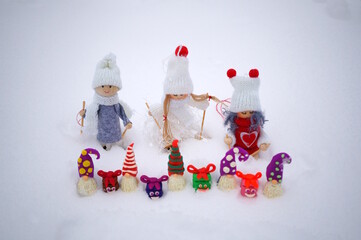 Wall Mural - Toy angels in knitted hats and scarves. There are dwarfs and gifts nearby. Christmas decorations. Snow background.