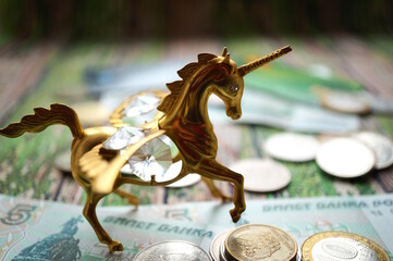 A unicorn statuette with coins on the table.