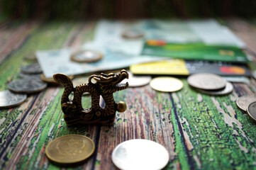 Wall Mural - A statuette of a metal dragon with coins on the table.