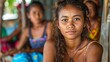 Women of East Timor Timor-Leste. Women of the World. A vibrant portrait of a young woman with a thoughtful expression, sitting in a tropical setting with other individuals slightly blurred in the back