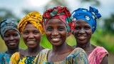Fototapeta  - Women of Mozambique. Women of the World. Four African women smiling joyfully in traditional headwraps and colorful clothing against a blurred natural background.  #wotw