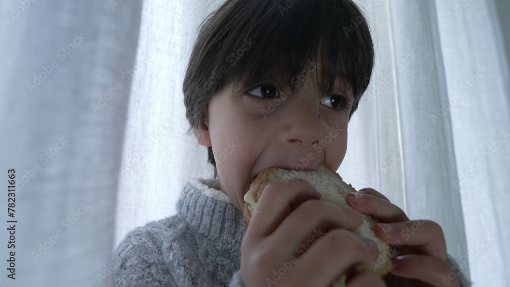 Child snacking sandwich, close-up hand and face of one small boy eating ...