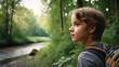 A young Caucasian child hikes through wilderness, carrying backpack, amidst forest, river, greenery; youth exploring, feeling amazed or unsettled, alone or lost.