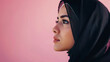 Portrait of a modest girl wearing hijab looking at copy space with a pink background