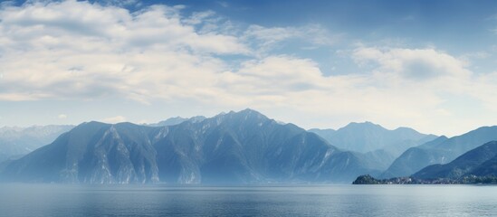 Fototapete - Mountains under serene cloudy sky at lake