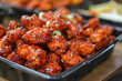 Tray filled to the brim with delicious chicken wings marinated in a spicy sauce. The wings are garnished with spring onion and sesame seeds