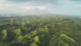 Fototapeta Natura - Aerial Philippines green jungle hills at Legazpi town, Asia. Tropical greenery forest with high trees, plants, grass and moss on ranges. Dusk summer day with cumulus grey clouds in dramatic shot