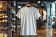 A white shirt hanging on a hanger in a store. The shirt is unbuttoned and has no design on it. The store is well lit and has a modern feel