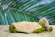 Podium texture stone for presentation of products and green leaves of palm. Blur and selective focus.