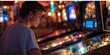 Young man absorbed in playing pinball in an illuminated arcade room. Recreation and gaming lifestyle concept.